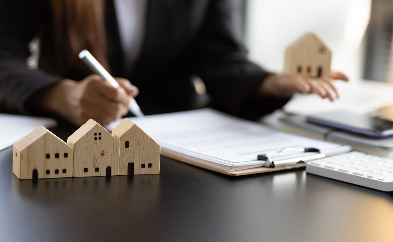 papers being signed out of focus with tiny houses
